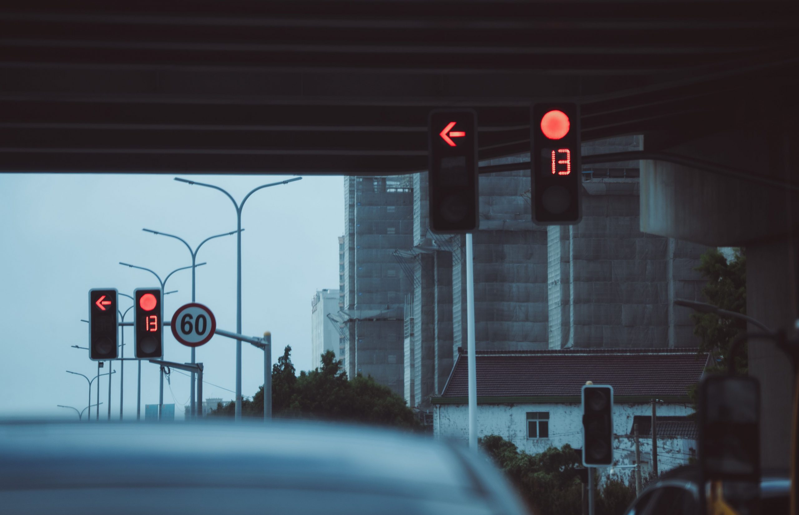Moody urban street scene with red traffic lights and countdown timer under a bridge.